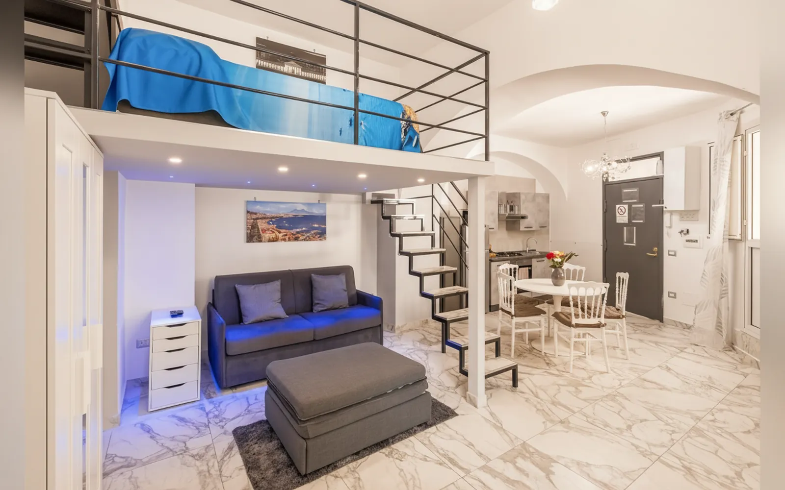 Vista d'insieme dell'appartamento con zona notte rialzata, divano e cucina