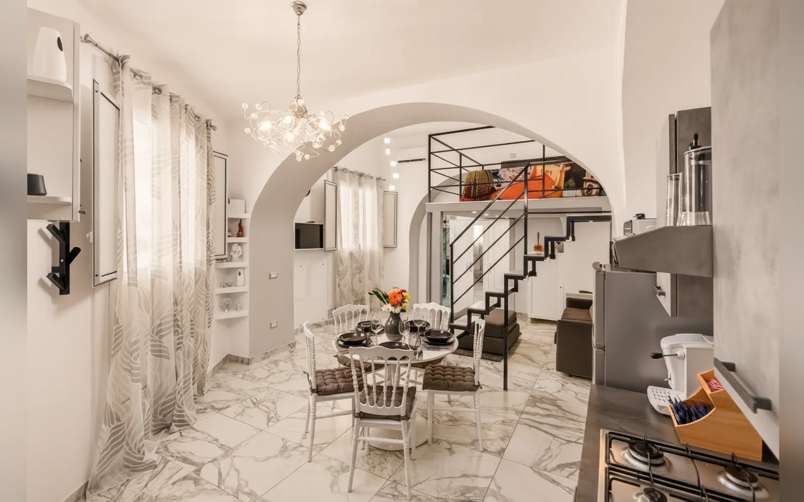 Zona pranzo con tavolo, cucina e scala verso la zona notte