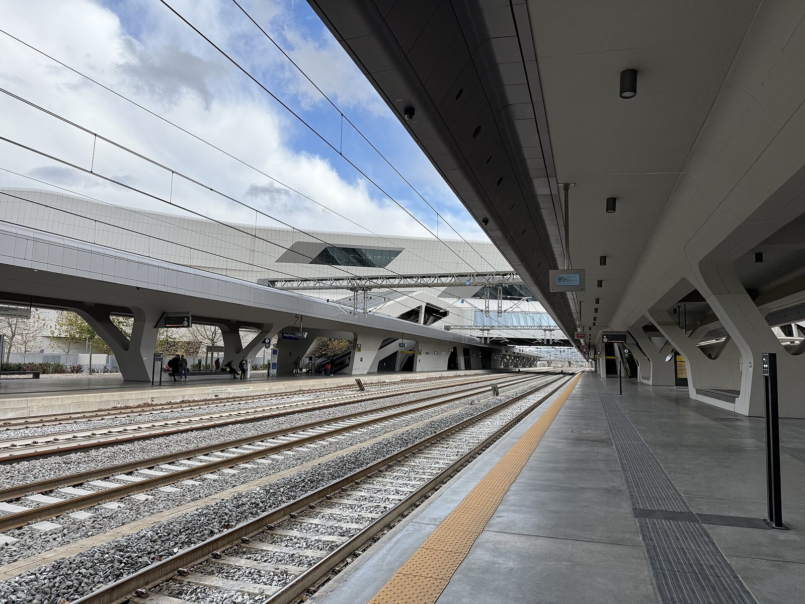 Binari e pensiline della stazione alta velocità Napoli Afragola, con l'edificio bianco sospeso sopra i binari