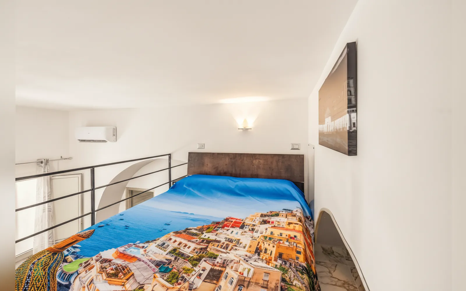 Letto matrimoniale con copriletto colorato e climatizzatore